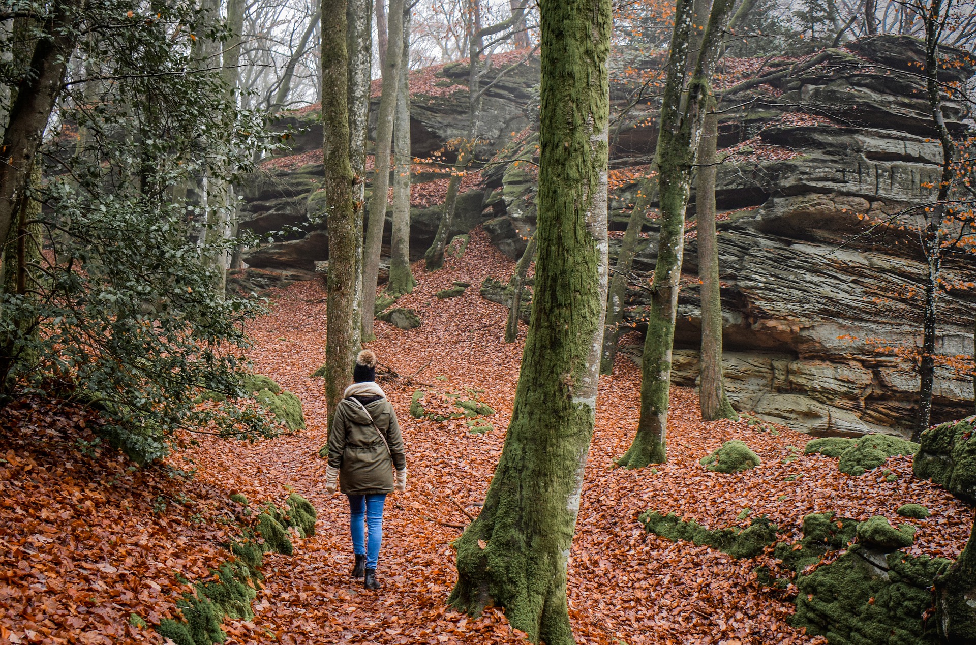Woman walking in forest with fall leaves on ground